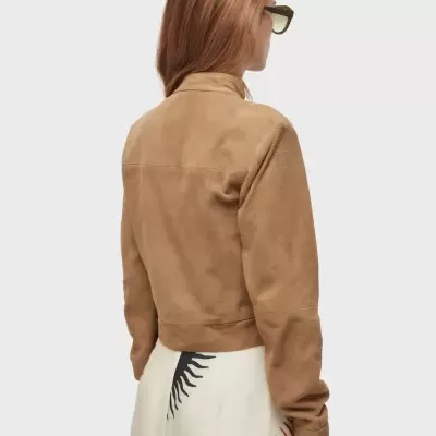 Casaco castanho de tecido suave visto de costas com saia clara estampada.