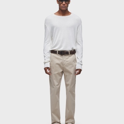 Homem com camisa branca, calças bege, óculos de sol e sapatos brancos.