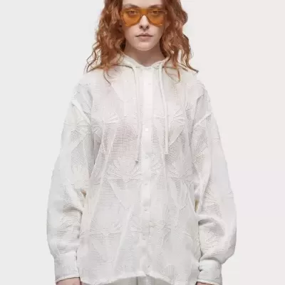 Conjunto feminino branco translúcido com camisa de capuz e calções, mulher com óculos laranja.