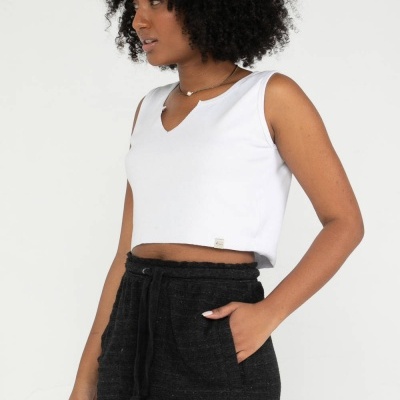 Mulher vestindo camisola branca cropped e shorts pretos com cordão, fundo branco.