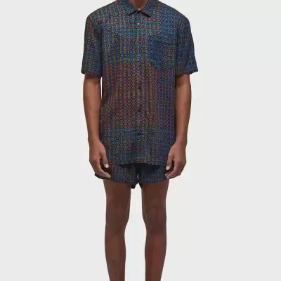 Homem a usar conjunto de camisa e calções com padrão colorido e óculos de sol