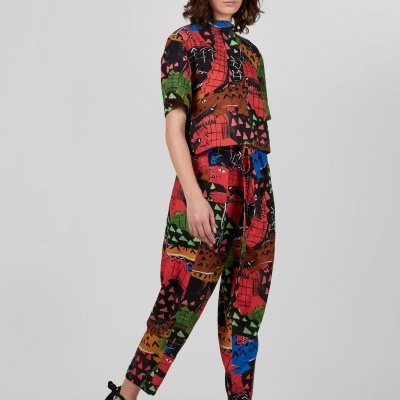 Conjunto estampado colorido com t-shirt e calças, sandálias pretas em fundo cinzento