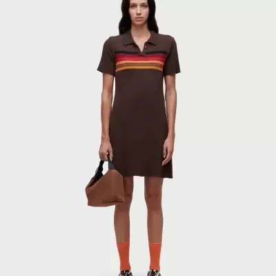 Mulher vestindo vestido curto castanho com riscas coloridas, meias laranja, ténis estampados e mala castanha