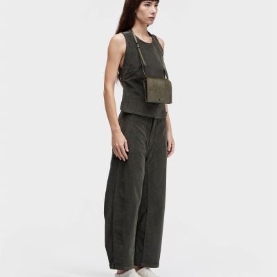 Mulher vestindo roupa verde e mala quadrada verde ao ombro