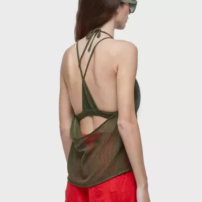 Mulher com top verde de malha e calças vermelhas curtas vista de costas.