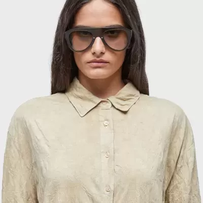 Óculos de sol pretos estilo aviador numa mulher com camisa bege clara