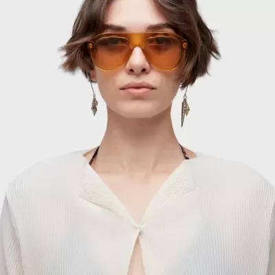 Óculos de sol castanhos em modelo com blusa branca e cabelo curto