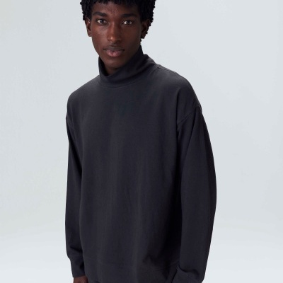 Homem com camisola preta de gola alta em fundo branco