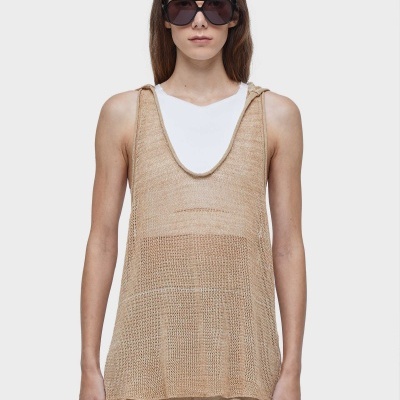 Regata ampla de malha bege transparente com camiseta branca e calças bege, óculos de sol escuros, fundo branco.