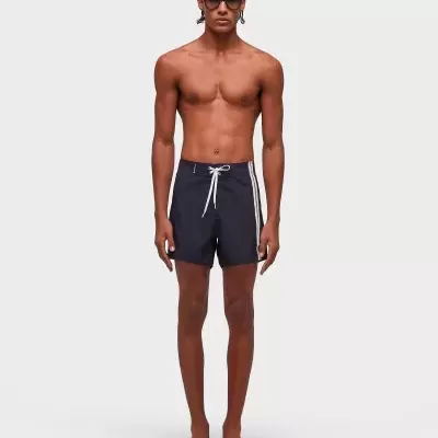 Homem com fatos de banho pretos de riscas brancas e óculos escuros.