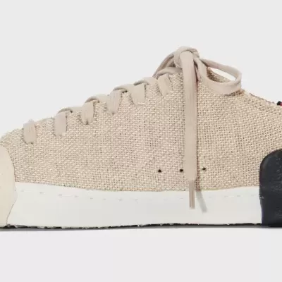 Tênis de tecido bege com sola branca e reforço preto no calcanhar