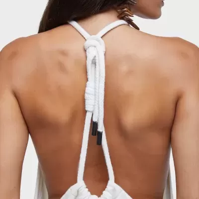 Vista traseira de mulher com vestido branco com alças de corda amarradas no pescoço