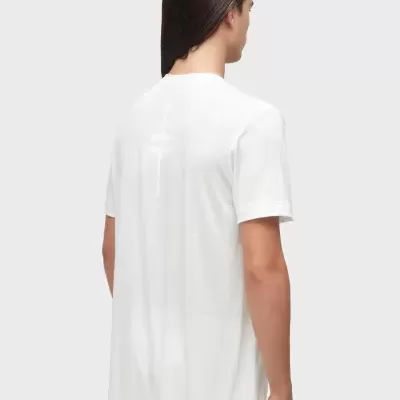 Modelo de costas a usar t-shirt branca com estampa branca pouco visível e calça branca