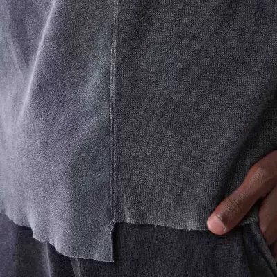 Conjunto de roupa cinzenta em tecido suave com costura e bainha irregular, mão pousada