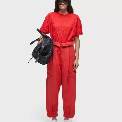 Mulher com roupa vermelha, ténis brancos, óculos de sol e mala preta