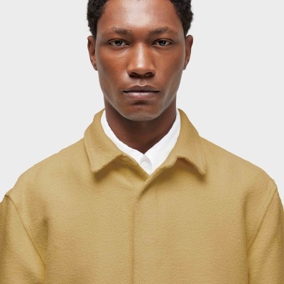 Homem com casaco bege felpudo e camisa branca, fundo branco