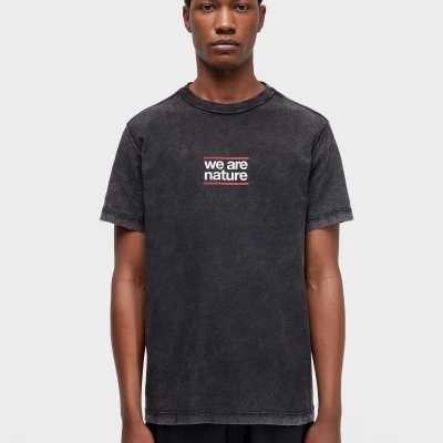 Homem a usar t-shirt preta com texto WE ARE NATURE ao centro e calças pretas