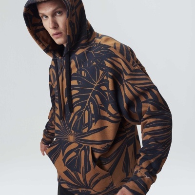 Homem de capuz com sweatshirt castanha e preta com padrão de folhas grandes