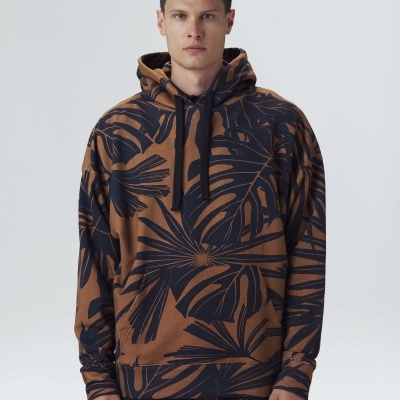 Homem a usar sweatshirt com capuz castanho com padrão de folhas pretas