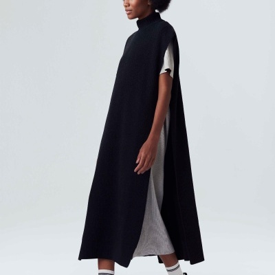 Mulher a usar vestido longo de malha preta com aberturas laterais, vestido cinzento por baixo, meias brancas e ténis pretos