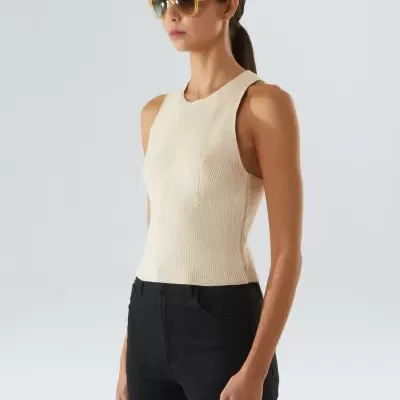 Mulher com top creme, calças pretas e óculos de sol amarelos