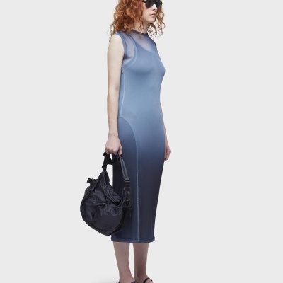 Mulher com vestido azul midi, óculos escuros e mala preta