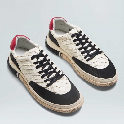 Sapatilhas brancas com textura de escamas, detalhes em preto, sola bege e calcanhar vermelho