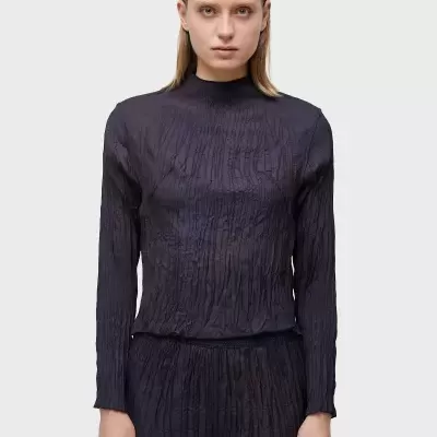 Camisola preta de manga comprida e gola alta com textura frutada usada por mulher.