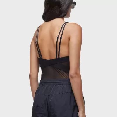 Mulher de costas com body preto de alças e calças largas pretas