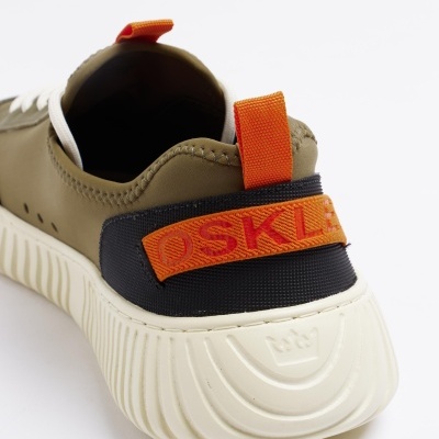 Ténis com sola branca, tecido verde-oliva, alça preta e tira laranja OSKLEN
