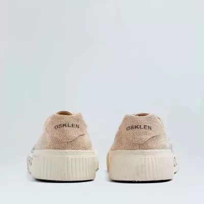 Ténis bege de lona com sola branca vistos de trás