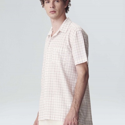 Homem com camisa clara de manga curta com padrão de quadrados finos