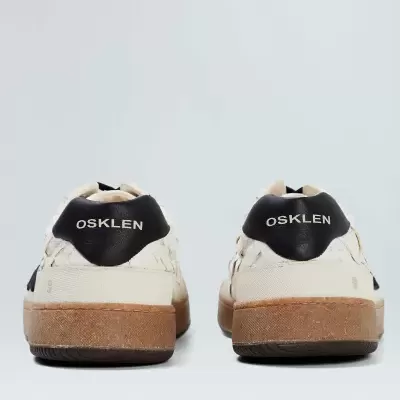 Ténis branco com parte traseira preta e logo OSKLEN