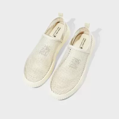 Sapatos desportivos bege em malha, sem atacadores, com sola branca.