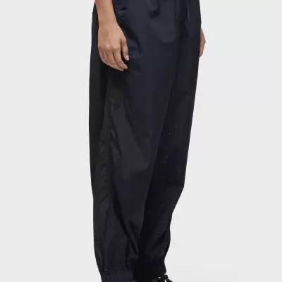 Calças desportivas pretas com punhos elásticos usadas com ténis pretos e brancos