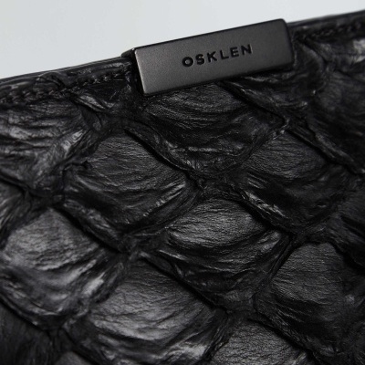 Produto em pele preta texturizada com placa metálica OSKLEN