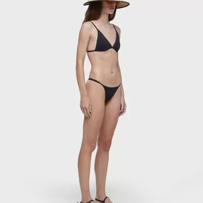 Mulher com fato de banho preto, chapéu de palha e sandálias pretas