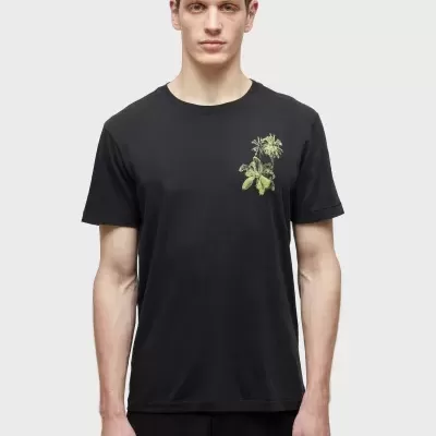 Homem a usar t-shirt preta com estampado verde de folhas no peito