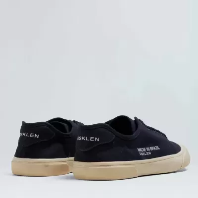 Ténis pretos Osklen com sola bege em fundo neutro