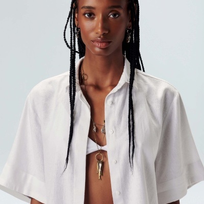Mulher com camisa branca de manga curta e colares dourados