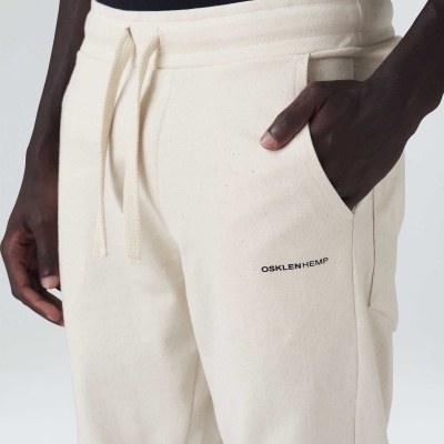 Calças bege claro com cordão na cintura e texto 'OSKLEN HEMP' no bolso lateral