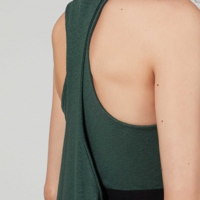 Top desportivo verde escuro com costas à mostra em fundo cinza