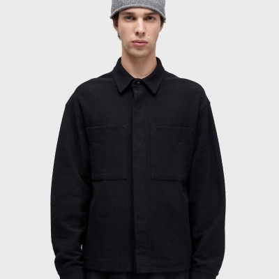 Homem com gorro cinzento e camisa preta com bolsos frontais