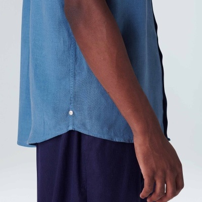 Pessoa de camisa azul e calças azul escuro em fundo branco