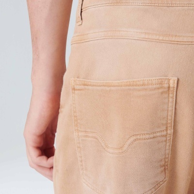 Calças bege em tecido jeans com bolso traseiro e costuras visíveis