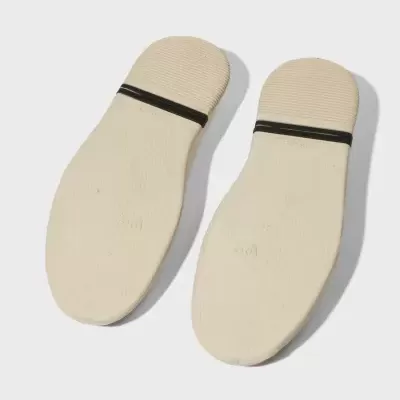 Solados creme de sapatos com faixa preta sobre fundo branco.