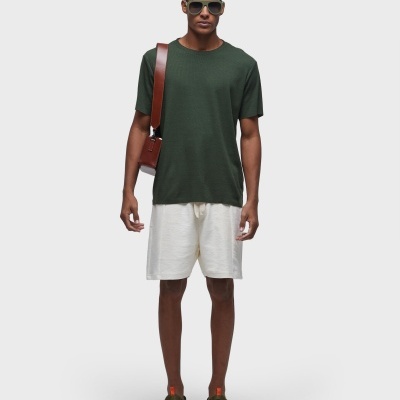 Homem com t-shirt verde, calções brancos e óculos escuros