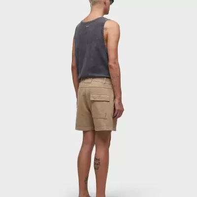 Homem de costas com regata cinza, calções bege e chinelos pretos