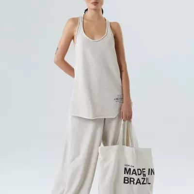 Mulher com conjunto bege claro e bolsa branca com texto preto