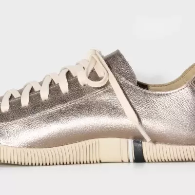 Sapatilha metálica dourada com atacadores brancos e sola de borracha creme